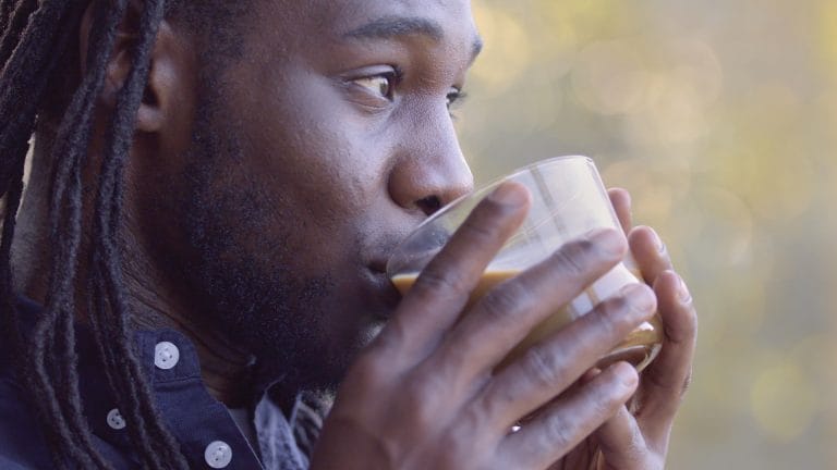 A young man drinking a cup of coffee with creamer