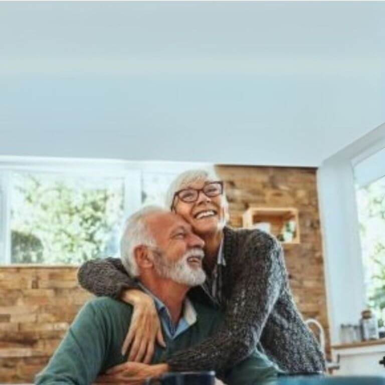 Elderly couple, one man and one woman embracing and smiling