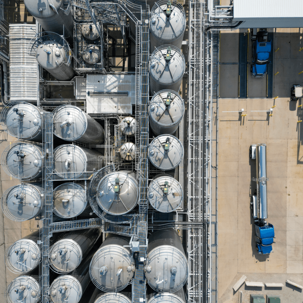 Aerial view of an industrial facility with large storage tanks and blue trucks, illustrating enzyme production infrastructure.