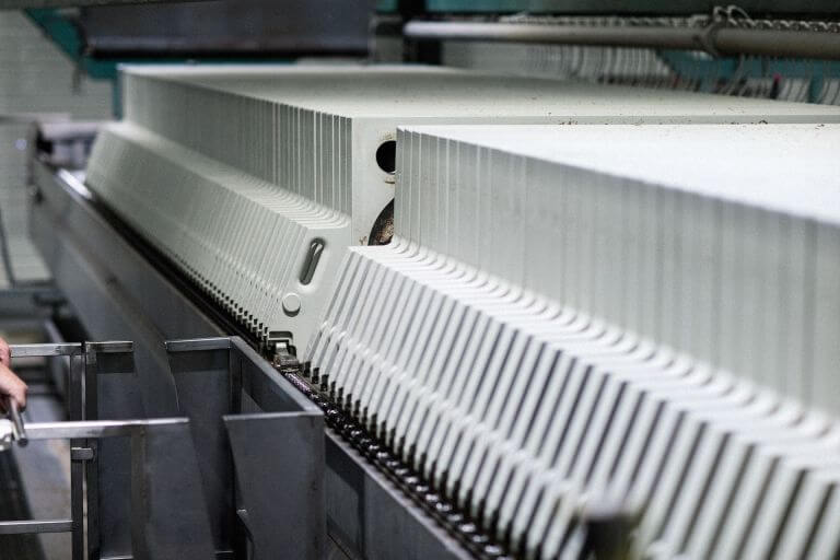 Close-up view of an industrial brewing filter press with multiple ridged plates and metal components in the background