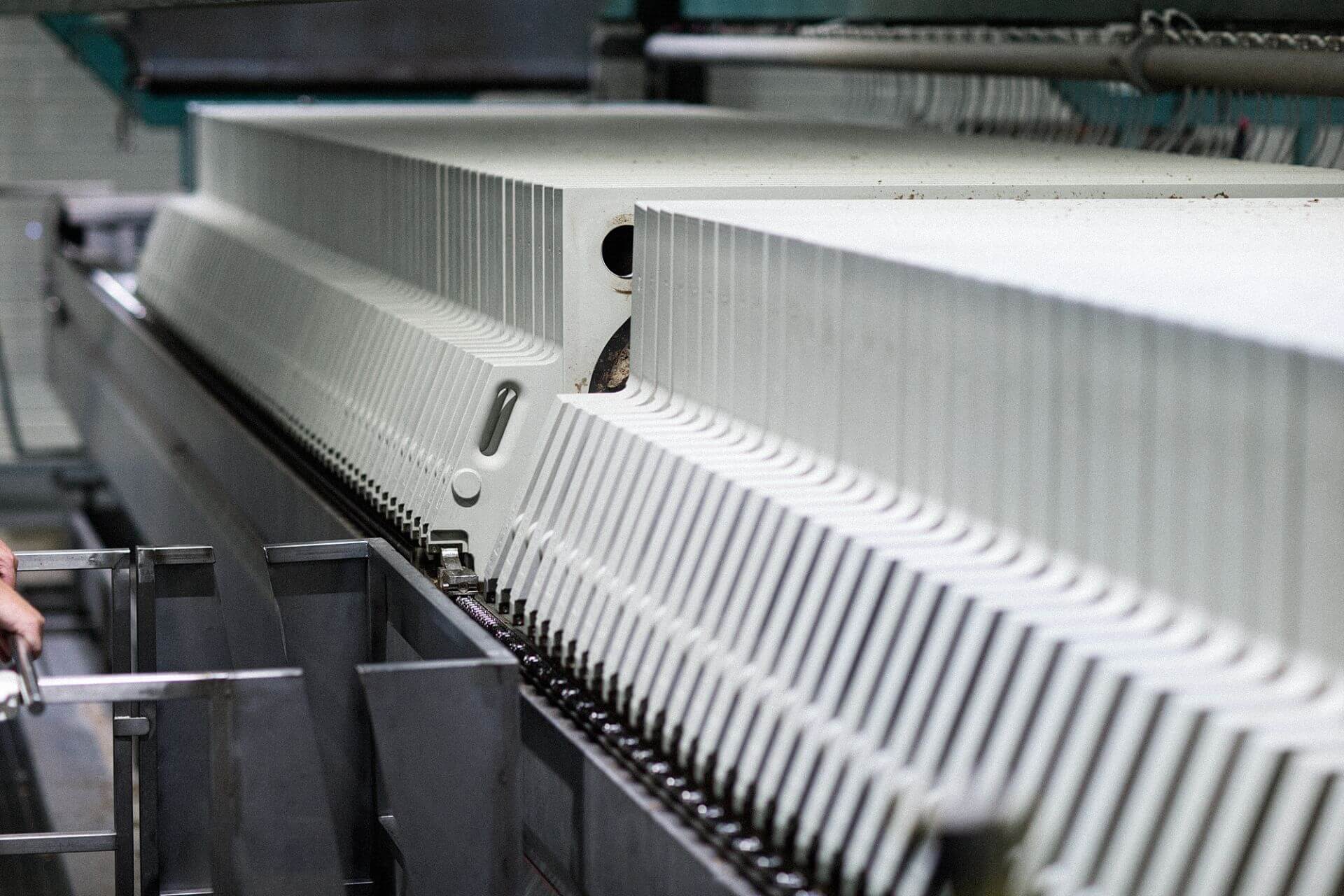 Close-up view of an industrial brewing filter press with multiple ridged plates and metal components in the background