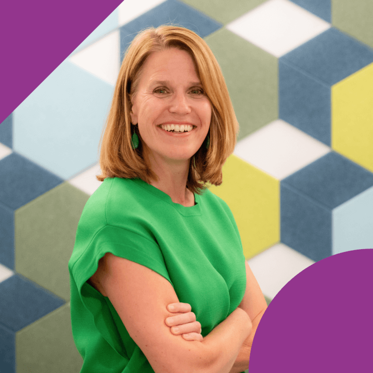 A woman with stands with arms crossed, wearing a green top, in front of a geometric patterned wall featuring blue, yellow, and white colors. The image has purple corner accents.