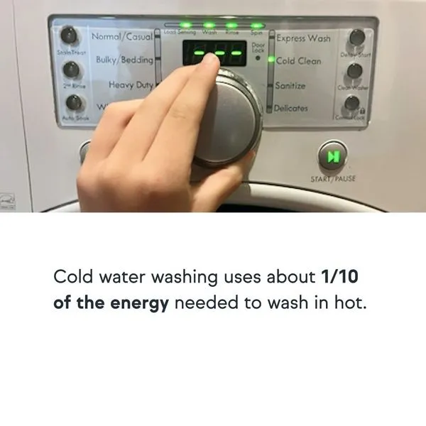 A hand turning the dial on a washing machine to select a cold water wash cycle.