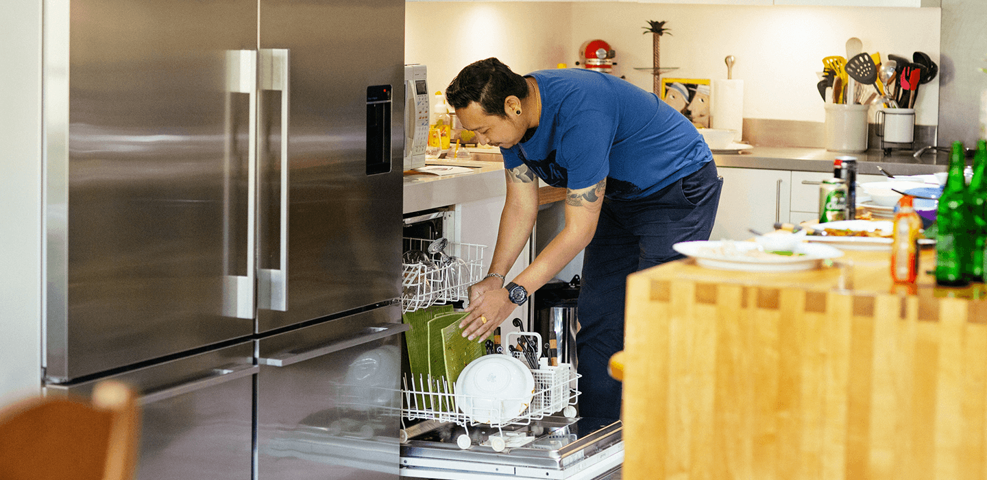Person loading dishes into a dishwasher in a modern kitchen.