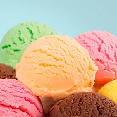 Close-up of colorful ice cream scoops in various flavors including green, yellow, pink, and brown against a light blue background.