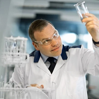 Scientist in a laboratory examining a glass beaker