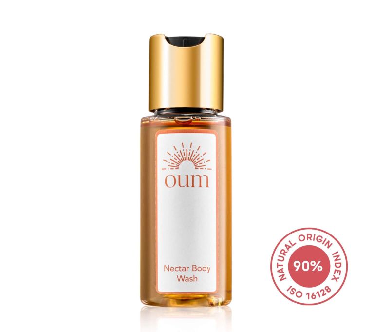 A small bottle of Oum Nectar Body Wash with a gold cap and a label displaying the brand name and product type. Next to the bottle is a red circular stamp indicating 