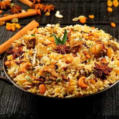A close-up of a plate of biryani garnished with star anise, cashews, and fresh herbs.