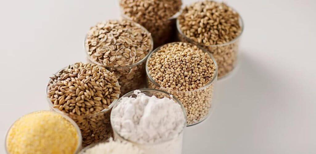 Various brewing & distilling grains in glass containers, including oats, millet, barley, and flour