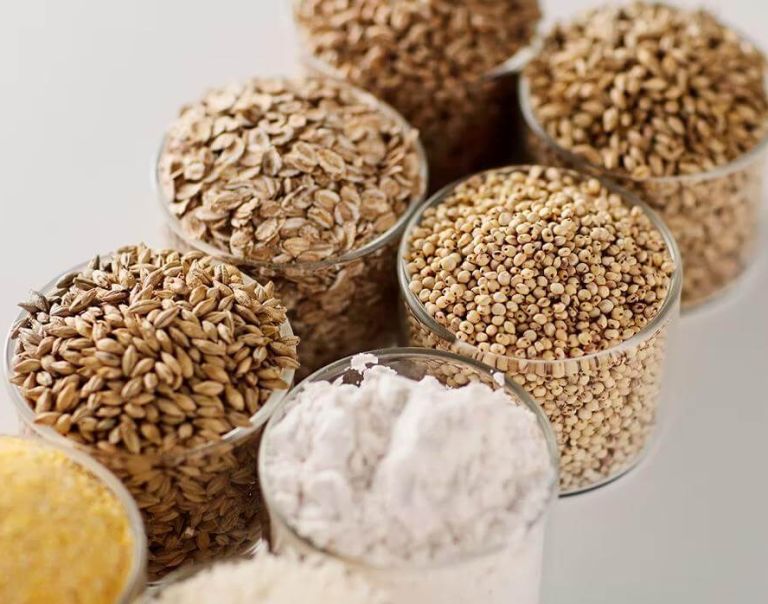 Various brewing & distilling grains in glass containers, including oats, millet, barley, and flour