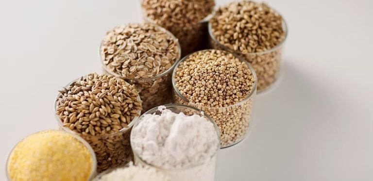 Various brewing & distilling grains in glass containers, including oats, millet, barley, and flour