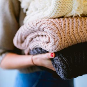 Close-up of a person holding neatly folded, high-quality knitted fabrics in various colors.