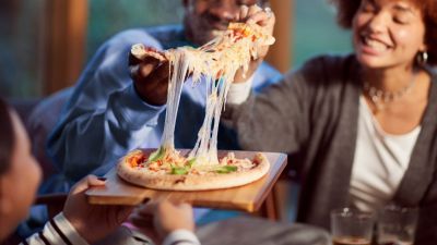 A group of friends enjoying a pizza with melted cheesing