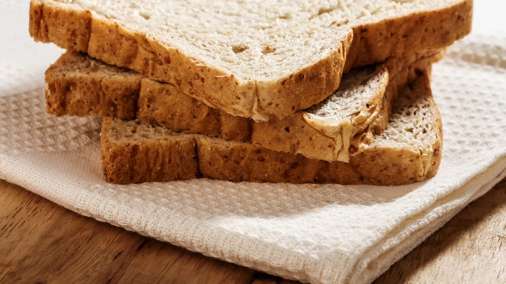 Slices of whole grain bread on a white textured cloth