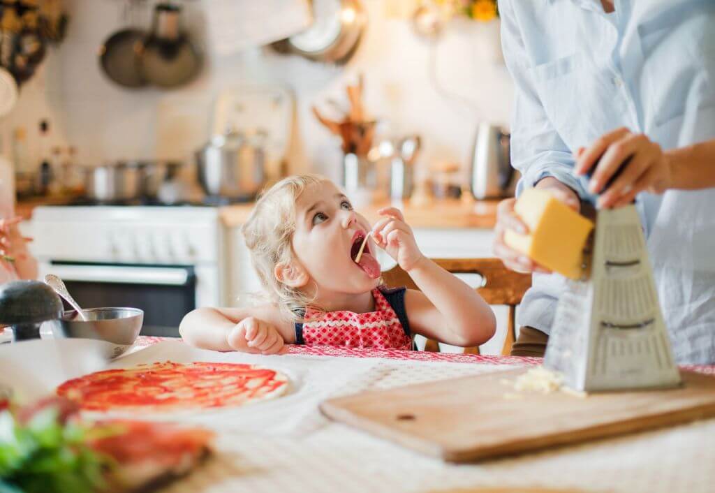 kid enjoying a piece of grated cheese