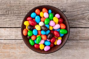 Bowl of brightly colored candy, sitting on a wooden table