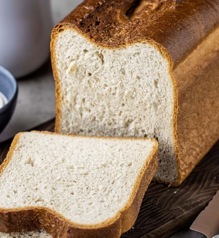 A loaf of bread with two slices cut from it, placed on a wooden cutting board