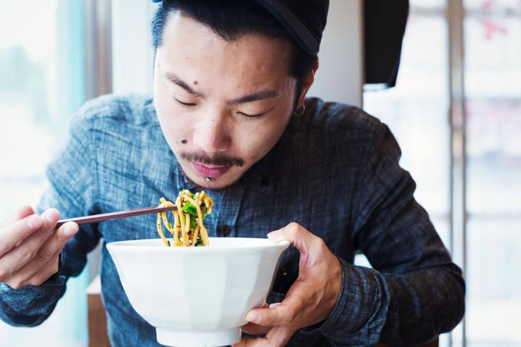 Man eating noodles flavored with FLAVORFIT [umami]