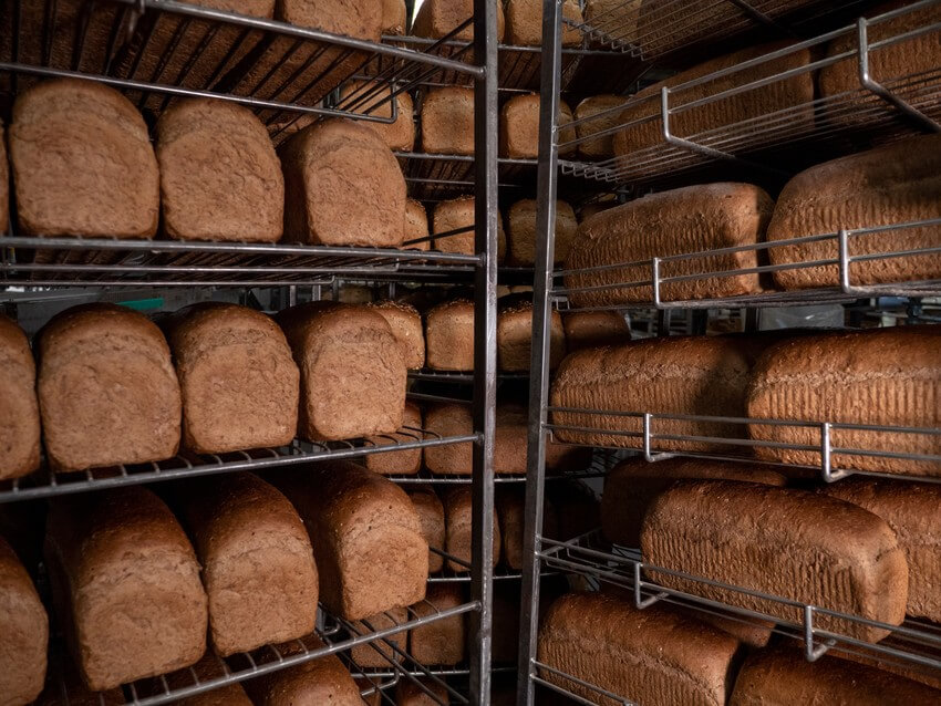Freshly baked loaves of bread cooling on wire racks in a commercial bakery