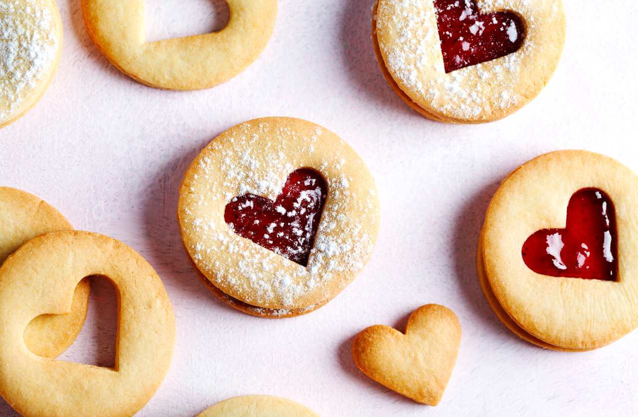 Heart-shaped Linzer cookies with red jam filling and powdered sugar on top